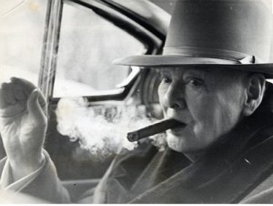 Winston Churchill blows out a cloud of cigar smoke.