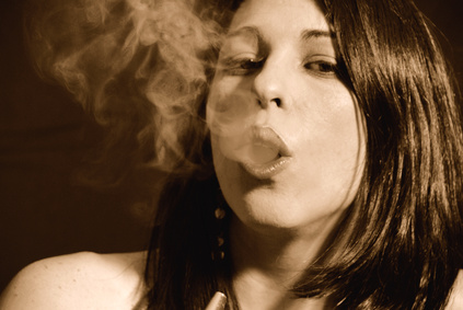 A girl inhales smoke. 