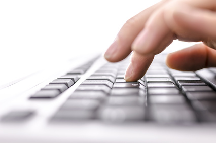 A woman's hands hover above a white keyboard. 