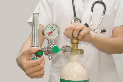 A nurse adjusts a medical oxygen tank.