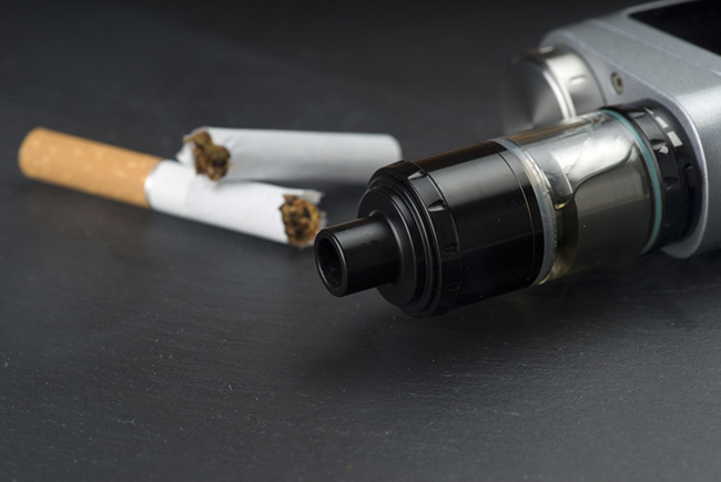 Cigarette snapped in half next to a vape mod