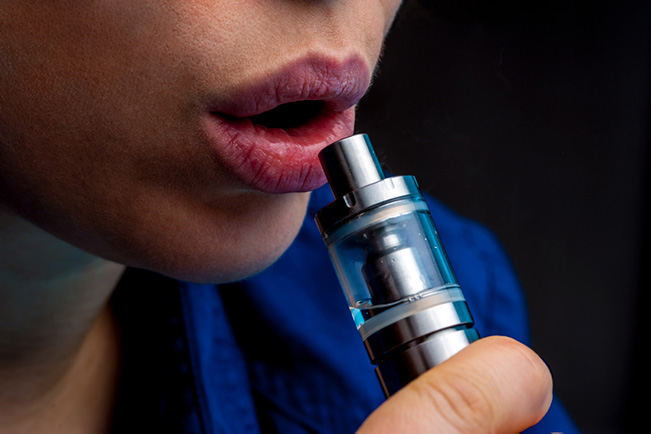 Close up of woman with vape tank by her lips