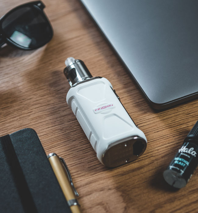 Innokin Adept Zlide, white, pictured on a table next to a laptop. 