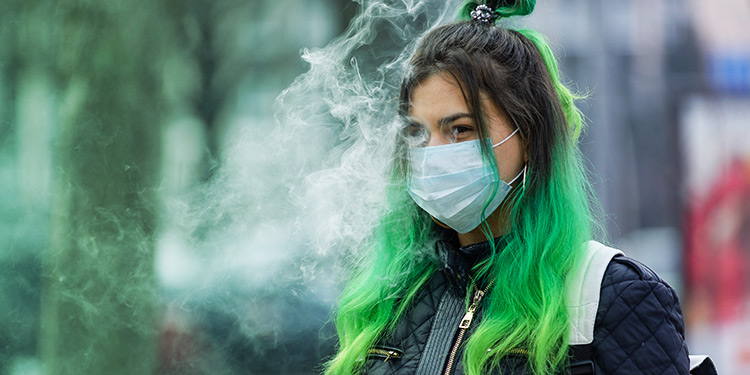 Girl in face mask surrounded by vapour.