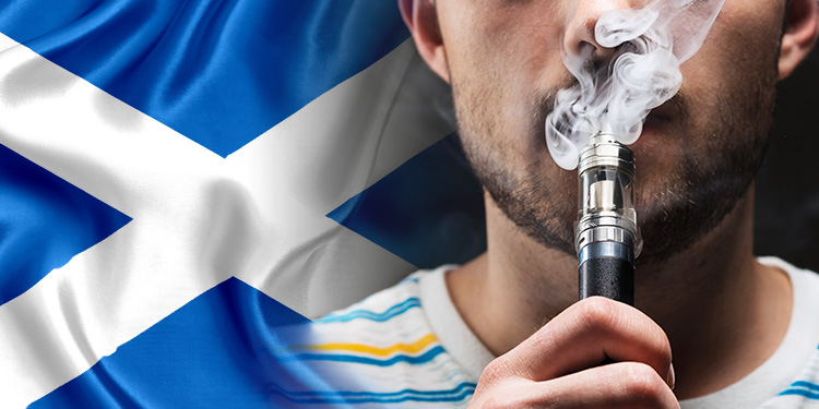 Man vapes in front of a Scottish flag.
