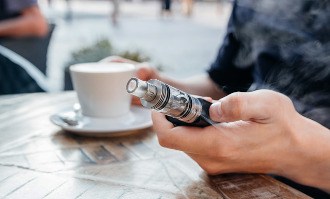 Hand holding a vape device at a cafe