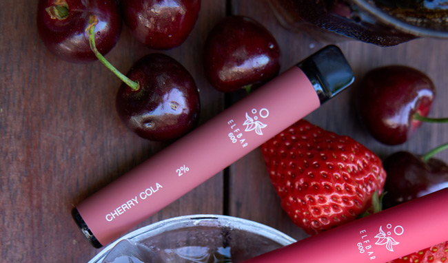 Image of a Cherry Cola Elf Bar disposable vape device amongst cherry and strawberry fruits