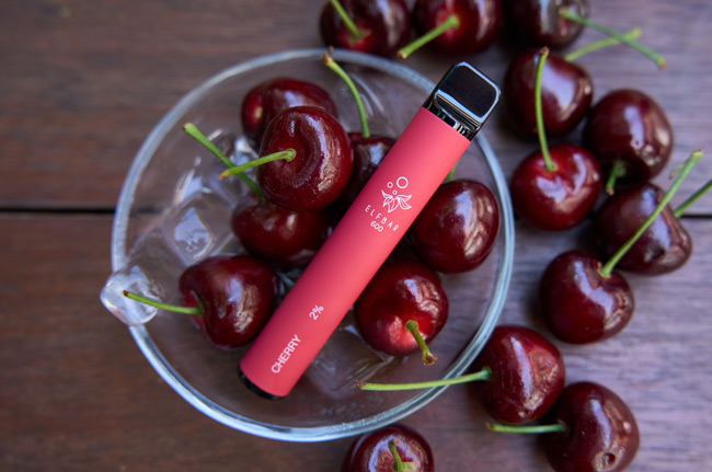 Image of a red-coloured Elf Bar disposable vape device in a bowl of cherries