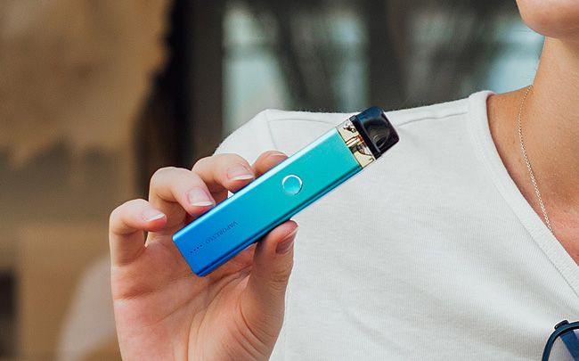 Blue Vaporesso Xros pod device held in hand. 