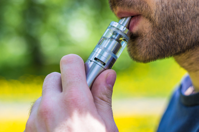 A man inhales on a refillable tank device. 